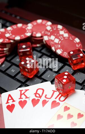 Casino chips, schede e dadi impilare su un computer portatile Foto Stock