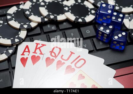 Casino chips, schede e dadi impilare su un computer portatile Foto Stock