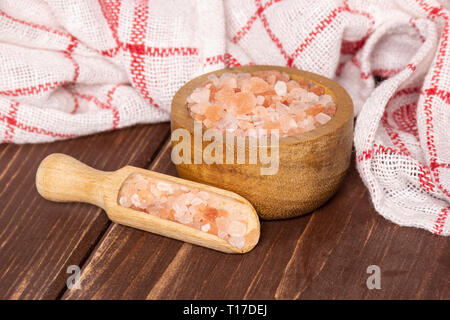 Lotto di pezzi di rosa himalayana di cristalli di sale in una ciotola di legno su legno marrone Foto Stock