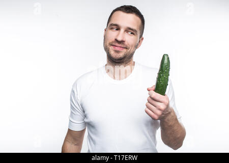 Allegra e felice ragazzo è in possesso di una grande e lunga cetriolo. Ama mangiare organico e alimenti naturali. Questo uomo è vegano. Cibo crudo è il suo preferito Foto Stock