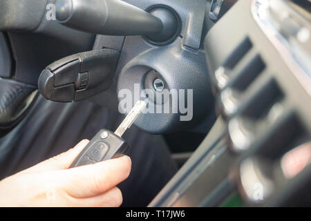 Primo piano interno veicolo della mano che tiene la chiave nel contatto, avviare il motore chiave. Foto Stock