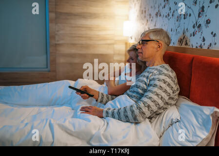 Amore maturo giovane a guardare la TV in camera da letto Foto Stock