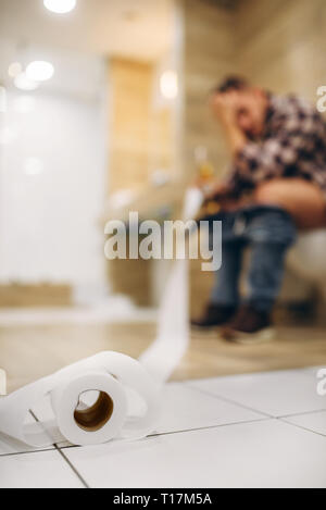 Triste uomo con i postumi della sbornia seduti sul wc Foto Stock