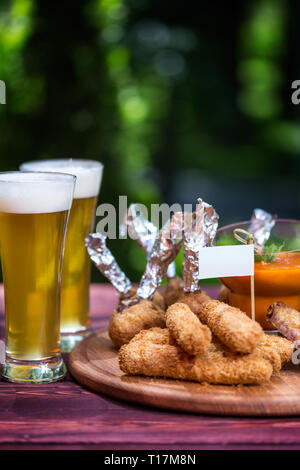 Pollo e formaggio impostato per la birra e due bicchieri di birra. Ali di pollo, formaggio bastoni e palline di formaggio con un luminoso ragù vegetale. Sul taglio Foto Stock