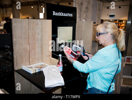 Donna di media età che adotta nuove tecnologie, auto-scansione per lo shopping e tecnologia touchscreen in un mercato in stile indoor Place.Gand, Belgio, Europa. Foto Stock