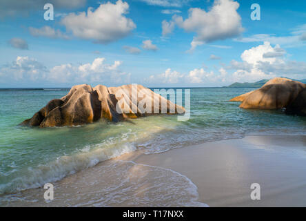 Onde turbinano intorno distintivo massi di granito su L'Anse Source d'Argent, La Digue, le Seychelles. Foto Stock