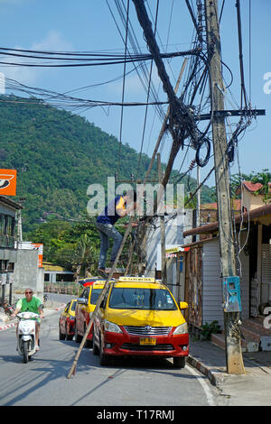 Elettrico si arrampica fino a ledder per riparare alimentatore, downtown, Lamai Beach, Koh Samui, Surat Thani, Golfo di Thailandia, Tailandia Foto Stock