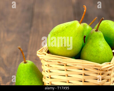 Una sana pere biologiche nel cestello sul legno scuro dello sfondo con spazio di copia Foto Stock
