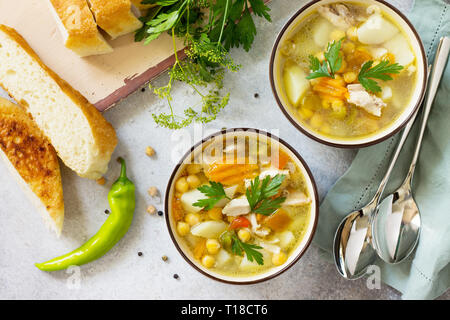 In casa la zuppa calda con verdure, pollo e Piselli Ceci. Cucina orientale. Il concetto di mangiare sano. Vista superiore piatta sullo sfondo dei laici. Foto Stock