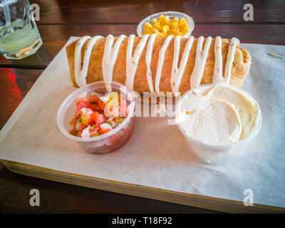 Chimichanga con una ricca salsa, mais e panna acida su legno che serve board Foto Stock