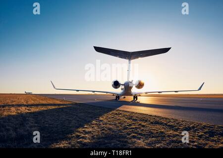 Aeroporto al tramonto. Silhouette di jet privato contro la pista. Foto Stock