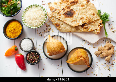 Tradizionale cibo indiano Samosa snack serviti in una piastra su un bianco tavolo di legno. India cibo background e texture con spazio di copia Foto Stock