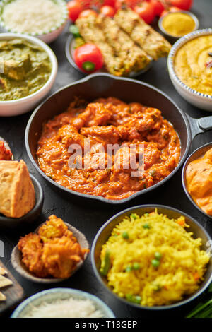 Vari piatti indiani su un tavolo. Piccante di pollo Tikka Masala in padella di ferro. Servito con riso, Naan e spezie. Set di diverso tipo cibo indiano. Foto Stock