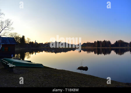 Cittadina nei pressi di un lago chiamato 'Soier vedere' durante il tramonto con una capella come pure una chiesa e barche Foto Stock