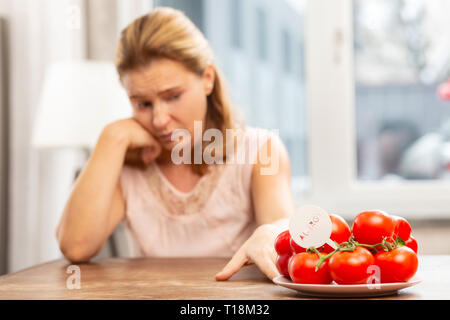 Donna sensazione di disagio avente allergia per i pomodori Foto Stock