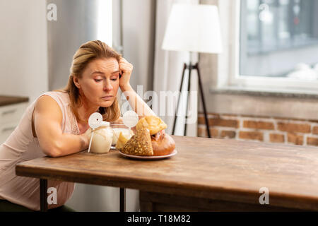 Sentimento donna fame guardando il pane e i panini ma avente allergia Foto Stock