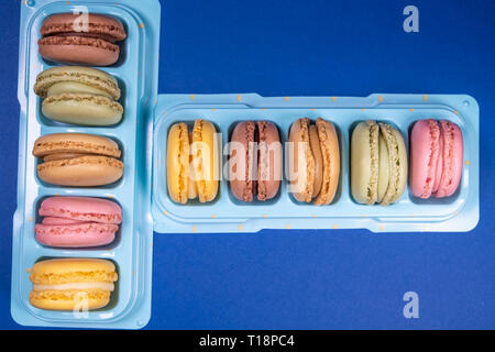 Colorati macarons francesi isolati su sfondo blu poste in vendita il vostro stand. Colori pastello - Immagine Foto Stock