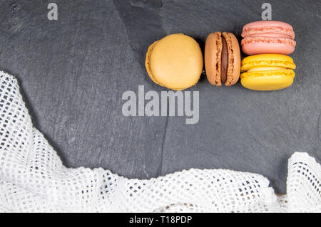 Assortiti francese colorati macarons isolati su lavagna sfondo in pietra con uno strofinaccio. Colori pastello - Immagine Foto Stock