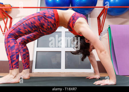 Giovane donna sportiva la pratica dello yoga, facendo stretching Chakrasana posizione in un fitnes club. Foto Stock