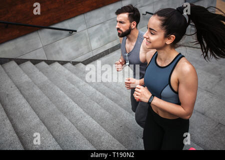Giovane uomo e donna sono il jogging. Essi sono in corso fino a passi. Il giovane è guardare dritto. Essi sono concentrati sul movimento in avanti Foto Stock