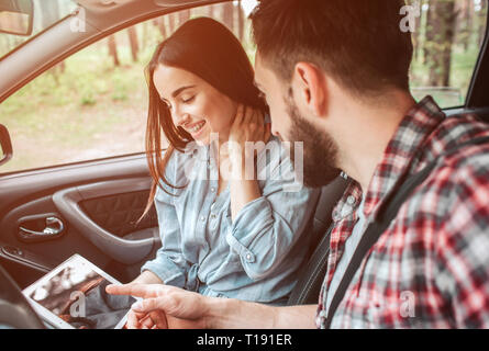 Bella ragazza è seduto con il suo fidanzato in auto e guardare lo schermo. Lei tiene la mano sul suo collo con gli occhi chiusi e sorridente. Lei si guarda ha Foto Stock