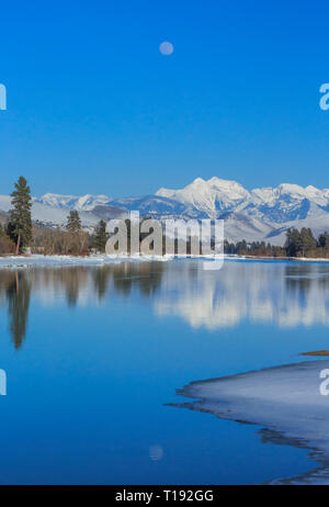 Luna crescente oltre il fiume flathead e missione le montagne in inverno vicino a Dixon, montana Foto Stock