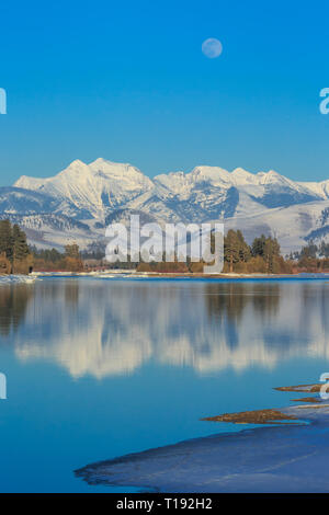 Luna crescente oltre il fiume flathead e missione le montagne in inverno vicino a Dixon, montana Foto Stock