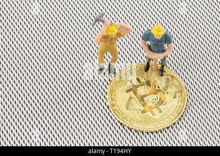 Close up macro shot di minatori figurina su bitcoins con argento metalizzato sfondo . cryptocurrency concetto. Foto Stock