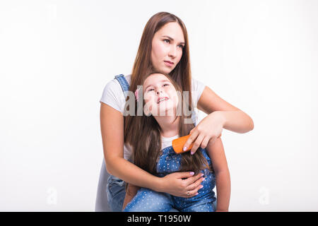 La famiglia, la maternità e il concetto di madre - madre la pettinatura la sua piccola figlia di capelli isolati su sfondo bianco Foto Stock