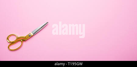 Bellezza parrucchiere concetto. Forbici con manico oro su sfondo rosa, banner, copia spazio, vista dall'alto Foto Stock