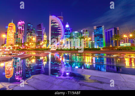 Capitale del Qatar. Colorato Doha West Bay sorge alto illuminata di notte riflessioni nel parco cittadino. New Scenic 5 posti le torri della skyline di Doha, Medio Oriente Foto Stock