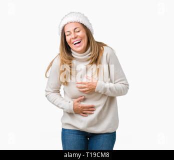 Bella la mezza età donna che indossa un maglione invernale e hat su sfondo isolato a sorridere e ridere hard out loud perché funny crazy scherzo. Felice Foto Stock