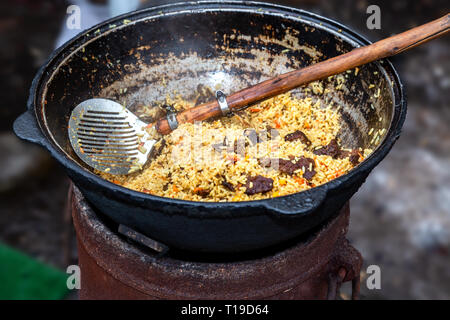Cucina tradizionale Uzbek pilaf in un gran calderone all'aperto Foto Stock