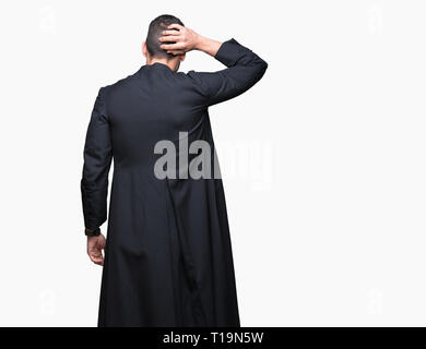 Giovane sacerdote cristiano su sfondo isolato indietro pensando di dubbio con la mano sulla testa Foto Stock