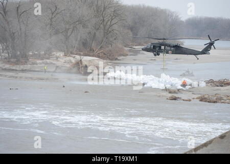 Un UH-60 Blackhawk elicottero si prepara ad abbassare il 1.500-pound sacchi di sabbia in posizione sull'argine 23 Marzo 2019 presso il fiume Loup, Nebraska. I sacchi di sabbia ha contribuito a prevenire fenomeni di erosione e di deviare il flusso di acqua lontano dall'impianto di alimentazione vicino a quella zona. (U.S. Air Force foto scattata dal personale Sgt. Natascia Hilsgen) Foto Stock