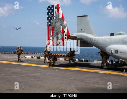 Golfo di Aden (23 marzo 2019) - USA Marines con il ventiduesimo Marine Expeditionary Unit forniscono sicurezza mentre esce da una MV-22 Osprey sul ponte di volo dell'Wasp-classe assalto anfibio nave USS Kearsarge (LHD-3) durante una tattica di recupero di aeromobili e di missione del personale prove. Il corso di formazione prepara Marines per inserire aree combattivo e recuperare o distruggere i materiali sensibili nonché recuperare personale. Marines e marinai con il ventiduesimo MEU e anfibio Kearsarge pronto Gruppo sono attualmente dispiegati per gli Stati Uniti Quinta Flotta area di operazioni a sostegno di operazioni navali per garantire mari Foto Stock