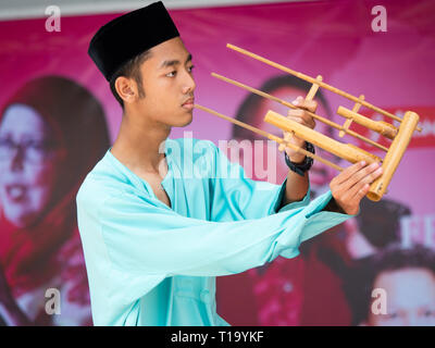 Uomo malese tenendo un angklung, un ritmo malese strumento fatto da bambù. Il angklung è costituito da due tubi di bambù insieme in una cornice di bambù. Esso Foto Stock