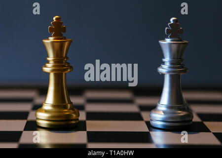 Immagine ravvicinata di oro e argento a scacchi kings posizionati l'uno contro l'altro sulla scacchiera Foto Stock
