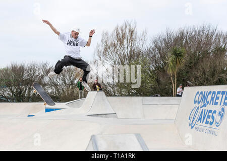 Un guidatore di skateboard tenta un trucco di antenna a onde Concrete Skate Park in Newqay in Cornovaglia. Foto Stock