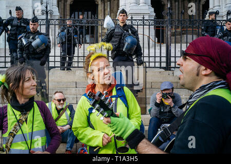 I manifestanti cantando prima di un gruppo di poliziotti a guardia dell'ingresso della Basilica del Sacre Coeur. Durante il XIX atto del francese Giubbotto giallo movimento, manifestanti a raccogliere le orme della Basilica Sacre Coeur, a nord di Parigi. Foto Stock