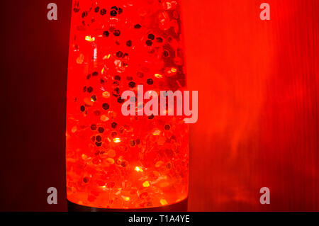 Arancione lampada lava con stelle luminose di notte su uno sfondo rosso, close up Foto Stock