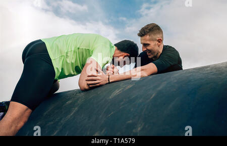 Gli uomini in un ostacolo corso arrampicata un tamburo Foto Stock