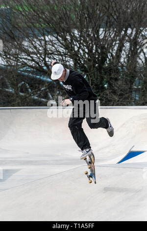 Un guidatore di skateboard tenta di eseguire un trick antenna a onde Concrete Skate Park in Newqay in Cornovaglia. Foto Stock