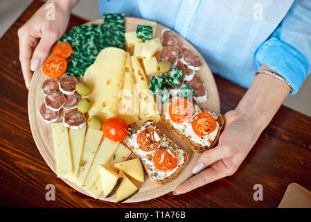 Close-up donna detiene un piatto di formaggio nelle sue mani. Foto Stock