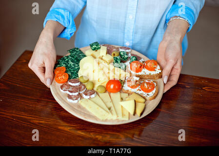 Close-up donna detiene un piatto di formaggio nelle sue mani. Foto Stock