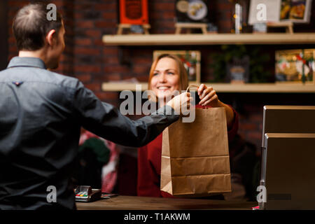 Immagine della ragazza venditore con sacchetto di carta e uomo shopper dal retro Foto Stock