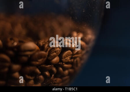 Nel macinino, ci sono un sacco di caffè in grani, sfondo nero, focus, i chicchi di caffè Foto Stock
