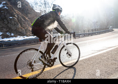 Professional bicicletta da strada racer in azione all'alba del giorno Foto Stock