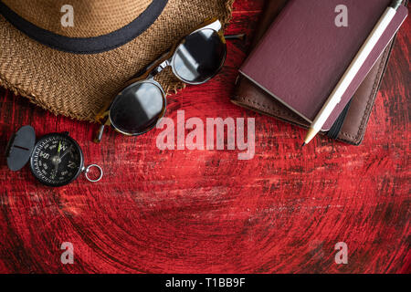 Set di passaporto ,notebook,occhiali da sole,bussola e matita bianca su rustiche in legno rosso tavola rotonda vicino alla finestra.Tropical Vacanze Estate Concetto di vacanza Foto Stock