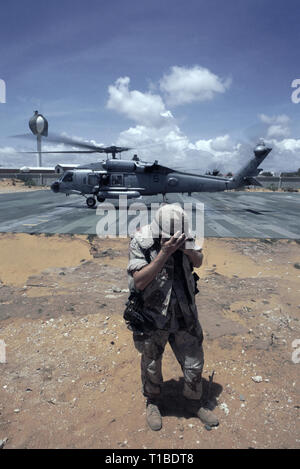 Il 29 ottobre 1993 A U.S. Soldato dell'esercito gira le spalle per la tempesta di sabbia come un US Navy Sikorsky SH-60 Seahawk elicottero dall'USS Abraham Lincoln decolla dall'heli-pad a UNOSOM HQ a Mogadiscio, in Somalia. Foto Stock
